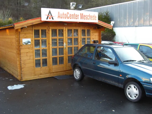 Das erste Büro in einer Holzhütte mit einem Auto davor